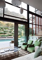 Salon moderne avec vue à travers les portes-fenêtres ouvertes sur la piscine
