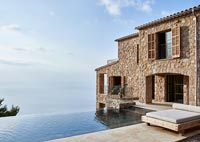 Extérieur de maison côtière en pierre avec piscine à débordement et vue sur la mer
