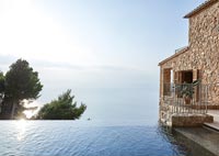 Extérieur de maison côtière en pierre avec piscine à débordement et vue sur la mer