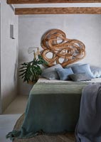 Sculpture en bois décorative sur le lit dans la chambre de campagne moderne