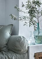 Vase en verre bleu de branches d'olivier sur le côté dans un salon de pays moderne
