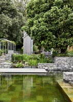 Mur de soutènement en pierre autour de l'eau dans un jardin de campagne moderne
