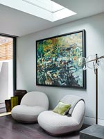 Chaises à coussin bas et grande peinture dans un salon moderne