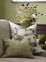 Coussin floral sur canapé avec des fleurs dans un vase derrière