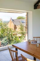 Table à manger en bois avec vue sur le jardin à travers de grandes fenêtres