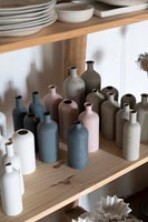 Collection de bouteilles en céramique dans des tons sourds sur étagère