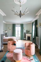 Coin salon rose sur tapis coloré dans une grande chambre peinte en vert