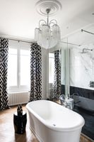 Baignoire autoportante et lustre dans la salle de bains moderne en noir et blanc