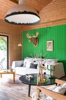 Tête d'animal trophée en bois sculpté sur un mur vert clair dans un salon moderne