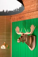 Sculpture tête d'animal mural sur mur en bois peint en vert