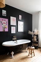 Mur caractéristique peint en noir dans une salle de bains moderne avec baignoire sur pieds