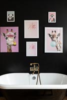 Photos colorées sur mur noir au-dessus de la baignoire dans la salle de bains moderne