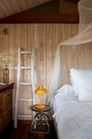 Échelle en bois décorative à côté du lit dans la chambre de campagne