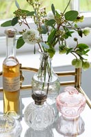 Fleurs dans un vase décoratif à côté de bouteilles de parfum vintage dans la salle de bains