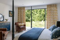 Lit à baldaquin dans une chambre moderne avec portes coulissantes donnant sur le jardin