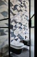 Vue dans salle de bains moderne avec carrelage à motifs sur le mur derrière les toilettes