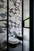 Vue dans salle de bains moderne avec carrelage à motifs sur le mur derrière les toilettes