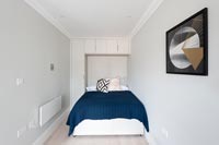 Petite chambre avec armoire intégrée et placards autour du lit
