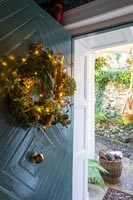 Guirlande décorée de guirlandes lumineuses sur la porte d'entrée de la maison de campagne