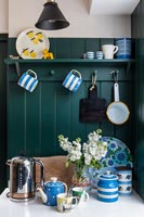 Vaisselle bleu et blanc dans une cuisine moderne avec mur peint en vert