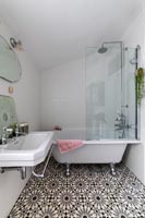 Salle de bain monochrome avec sol à motifs et baignoire sur pieds