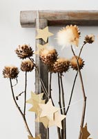 Étoiles d'or attachées autour des branches de fleurs en train de sécher pour Noël