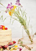Fleurs coupées dans un vase en verre à côté de gâteau sur la table