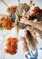 Femme créant un arrangement de fleurs séchées