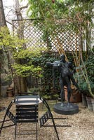 Grande statue dans le petit jardin de la cour avec table et chaises de style café