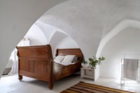 Chambre de campagne peinte en blanc avec alcôves et lit en bois
