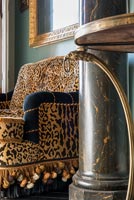 Canapé à imprimé léopard et colonne de marbre dans un salon éclectique
