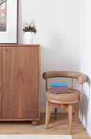 Petite chaise moderne rembourrée marron à côté du buffet en bois