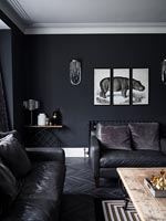 Un triptyque peinture d'hippopotame sur mur noir dans un salon moderne