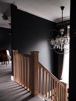 Escalier en bois avec murs peints en noir et lustre moderne