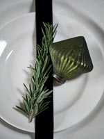 Boule verte et brin de romarin sur assiette pour Noël