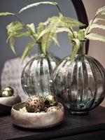 Feuillage dans un vase à côté de bol métallique de boules de Noël