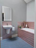 Salle de bain moderne avec carrelage rose sombre autour de la baignoire et du lavabo
