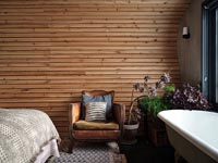 Fauteuil en cuir vintage et baignoire dans la chambre en bois