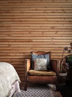 Fauteuil en cuir vintage par lambris en bois sur le mur de la chambre
