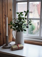Branches de houx avec des baies en cruche sur le rebord de la fenêtre à côté de cadeau emballé