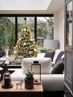 Arbre de Noël à côté de portes-fenêtres dans un salon moderne