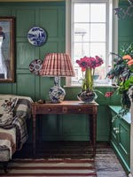 Fleurs et lampe sur table d'appoint antique dans un salon classique coloré