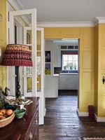 Vue dans la cuisine de la salle à manger lambrissée peinte jaune