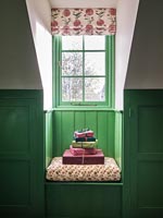 Cadeaux emballés sur petit siège de fenêtre avec des murs lambrissés peints en vert