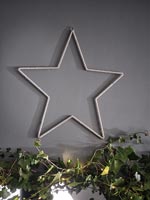 Étoile d'argent contre mur peint en gris avec décoration de Noël guirlande de lierre