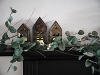 Guirlande de feuilles avec des lanternes en forme de petites maisons sur la cheminée