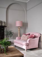 Canapé et lampadaire rose à côté d'un mur peint en gris