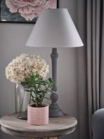 Plante d'intérieur et fleurs à côté de la lampe sur la table d'appoint ronde