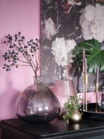 Branche avec têtes de graines noires dans un vase violet sur cheminée