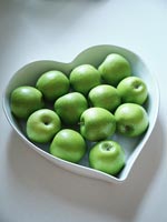 Bol de fruits blancs en forme de coeur rempli de pommes vertes